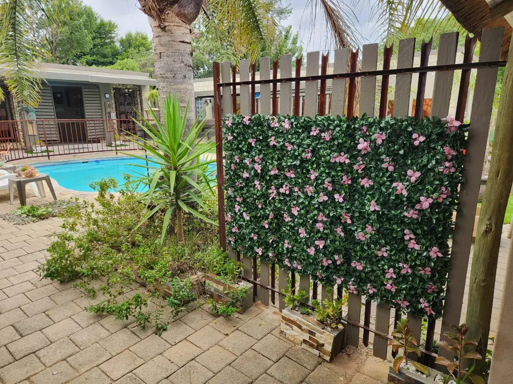 Freestanding floral poolside screen: A flowering hedge panel adds colour and partial screening beside the pool path and timber fence.