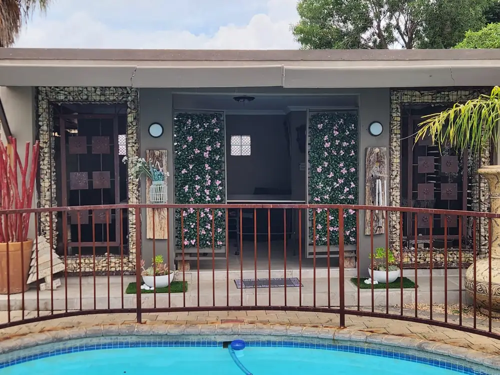 Matching floral panels across a pool: Two pink-flowering panels frame the building entrance on the far side of the pool fence.