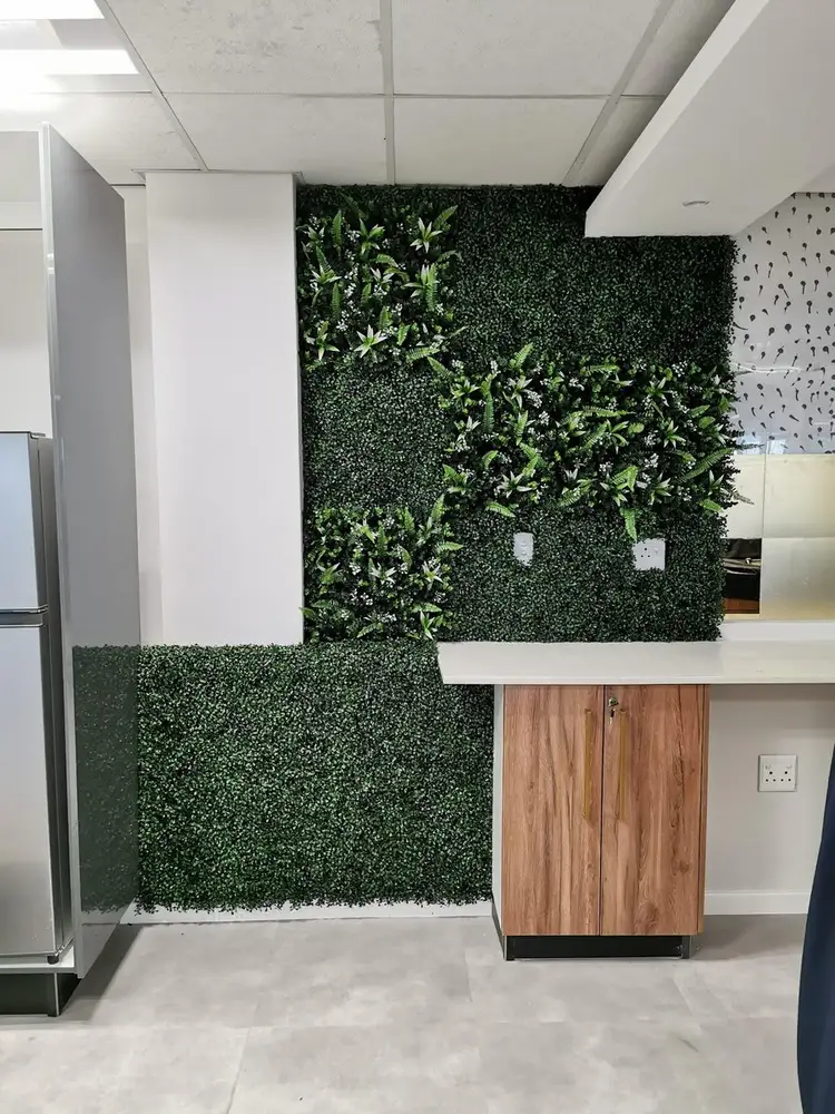 Reception counter and wall greenery: Artificial foliage is used both behind the reception counter and across its front for a coordinated finish.