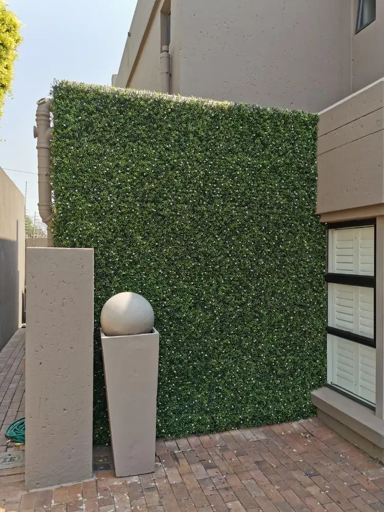 Tall freestanding entrance screen: A full-height rectangular hedge screen creates a green focal point beside the entrance and bollard lights.