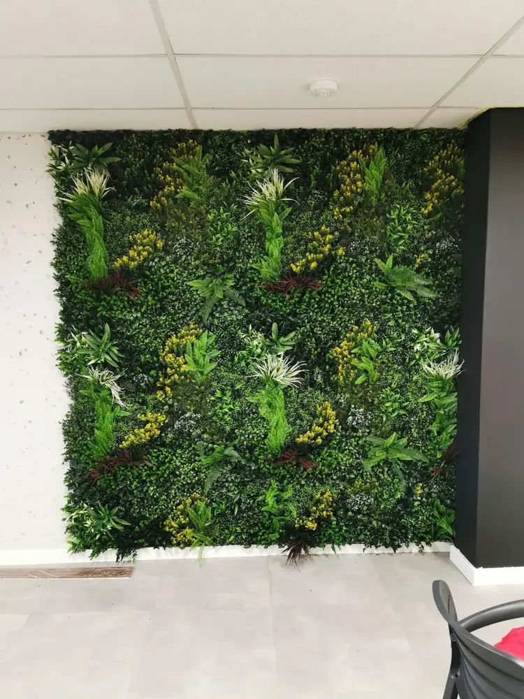 Indoor mixed-foliage statement wall: A floor-to-ceiling panel combines varied leaf shapes and green tones within a dark frame.