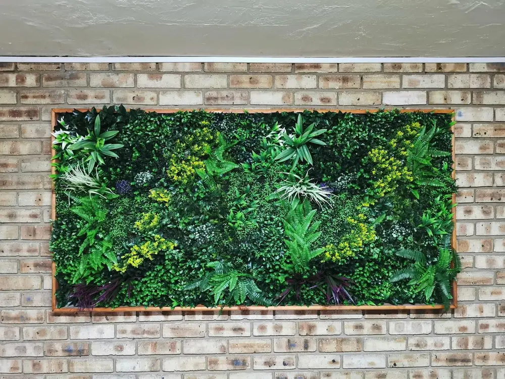Brick-framed botanical panel: A mixed-foliage panel is inset into a rectangular brick frame like an outdoor artwork.