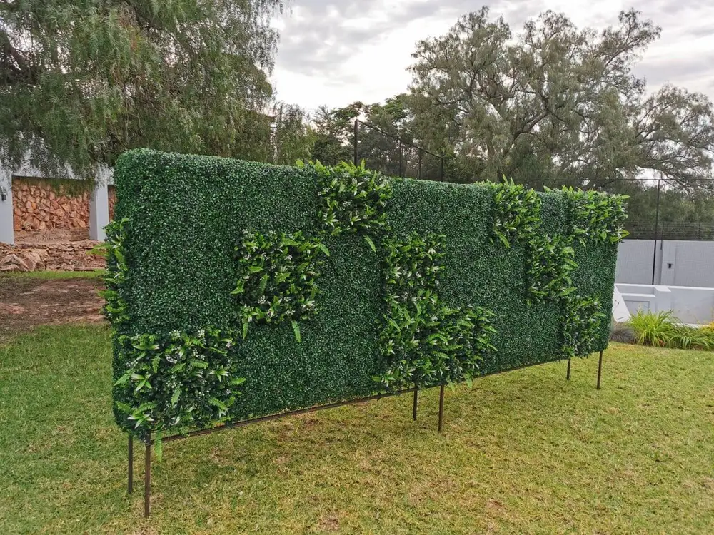 Freestanding garden divider with accent panel: A long privacy divider uses dense green panels with one contrasting mixed-foliage section.