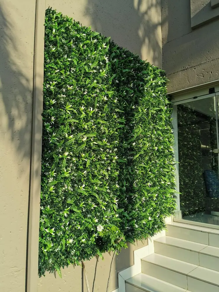 Framed entrance-wall panels: Two vertical foliage panels are mounted between light-coloured architectural columns beside the steps.